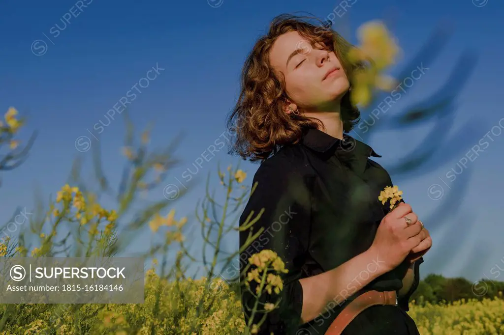 Portrait of teenage girl with eyes closed standing in rape field