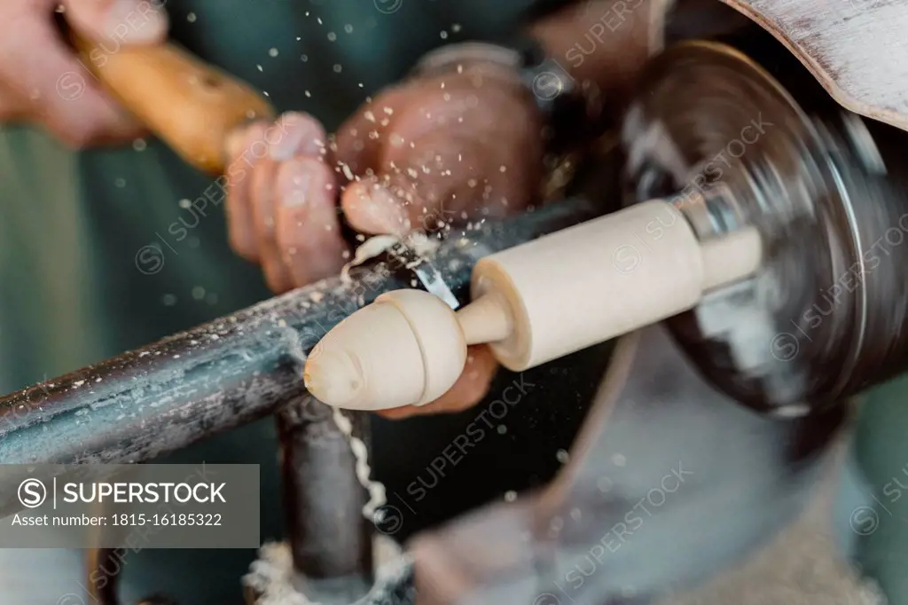 Close-up of carpenter holding chisel while shaping wood at workshop