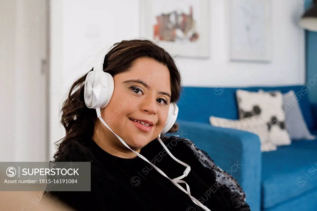 Happy woman with down syndrome listening music while relaxing in living room