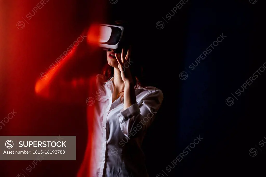 Young woman using VR glasses over black background