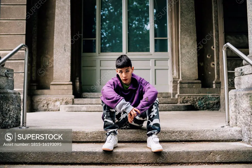 Cool confident man sitting on steps against house