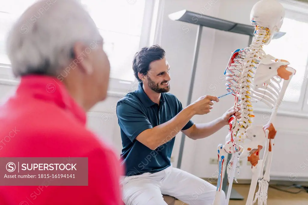 Physiotherapist explaining treatment to patient, using skeleton