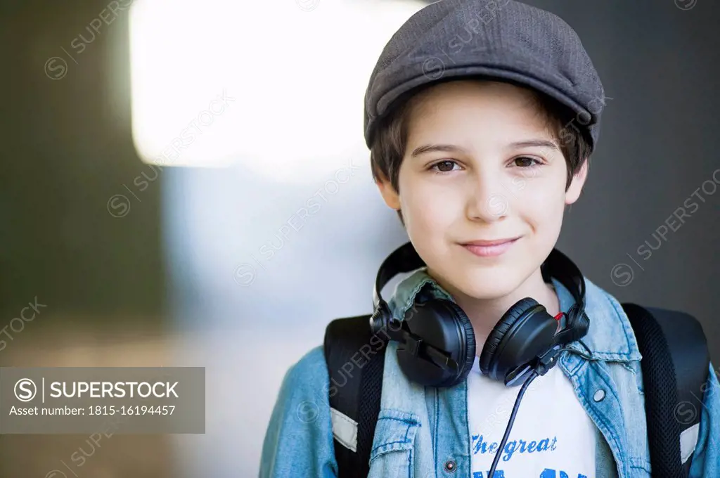 Confident boy wearing headphones around neck outdoors SuperStock