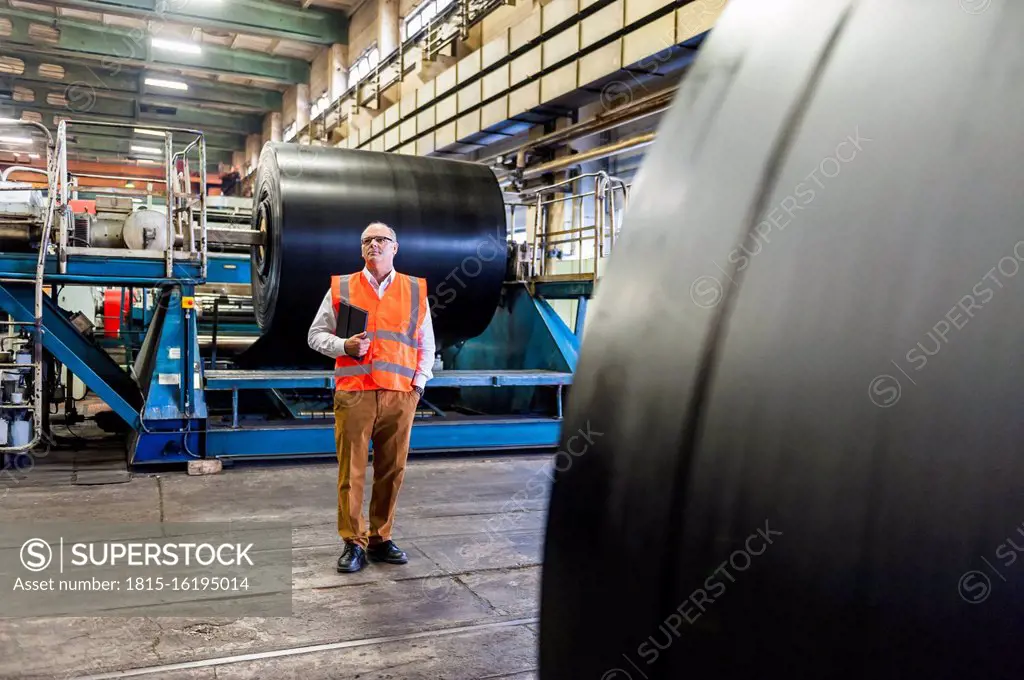 Senior man wearing safety vest in a rubber processing factory