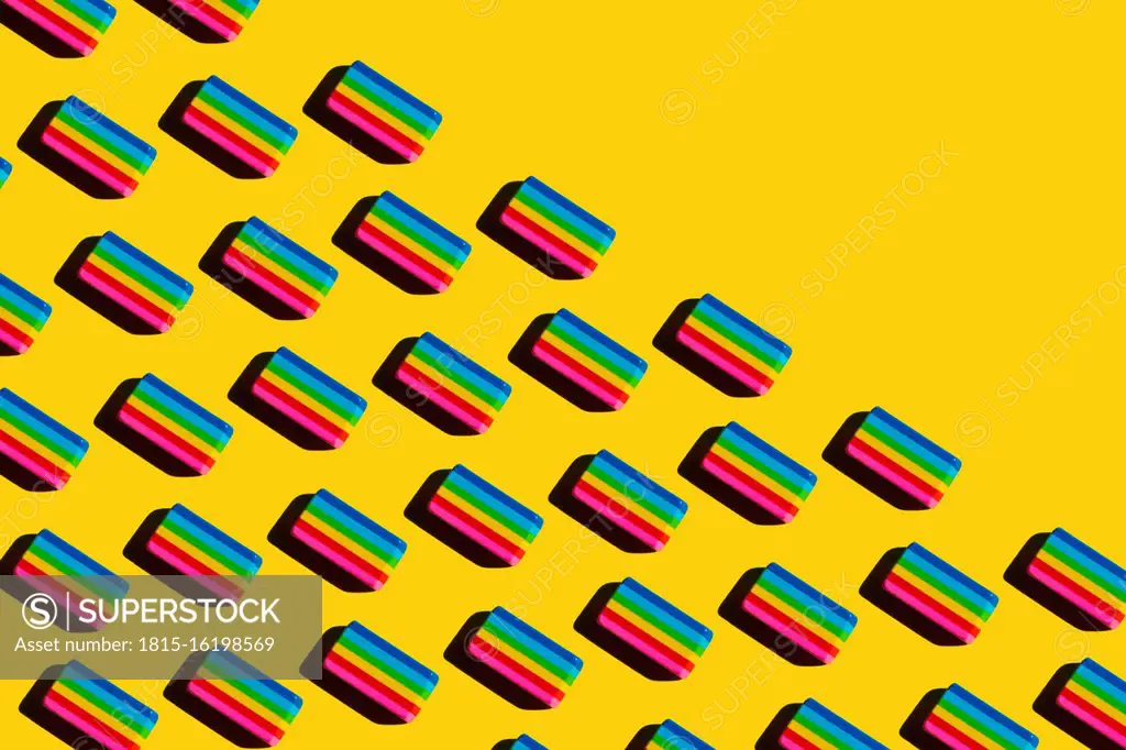 Pattern of rainbow colored erasers against yellow background