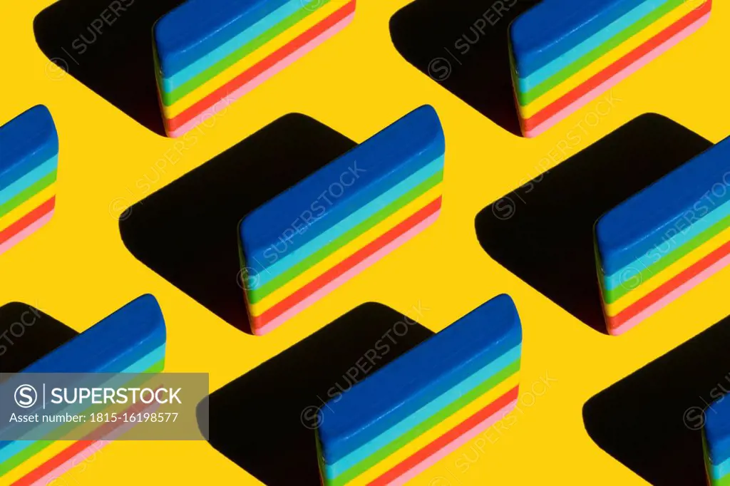 Pattern of rainbow colored erasers against yellow background