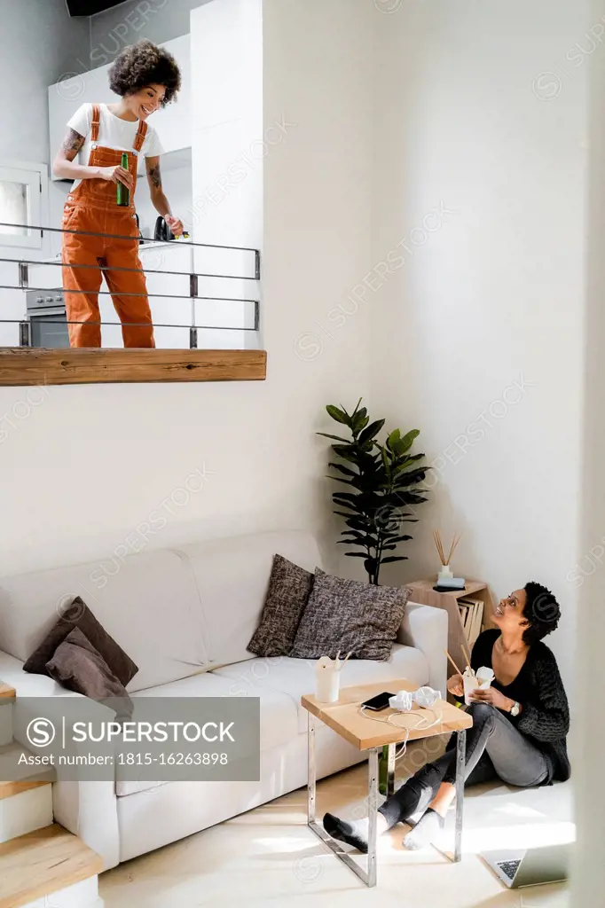 Two young women relaxing at home with Asian food and beer