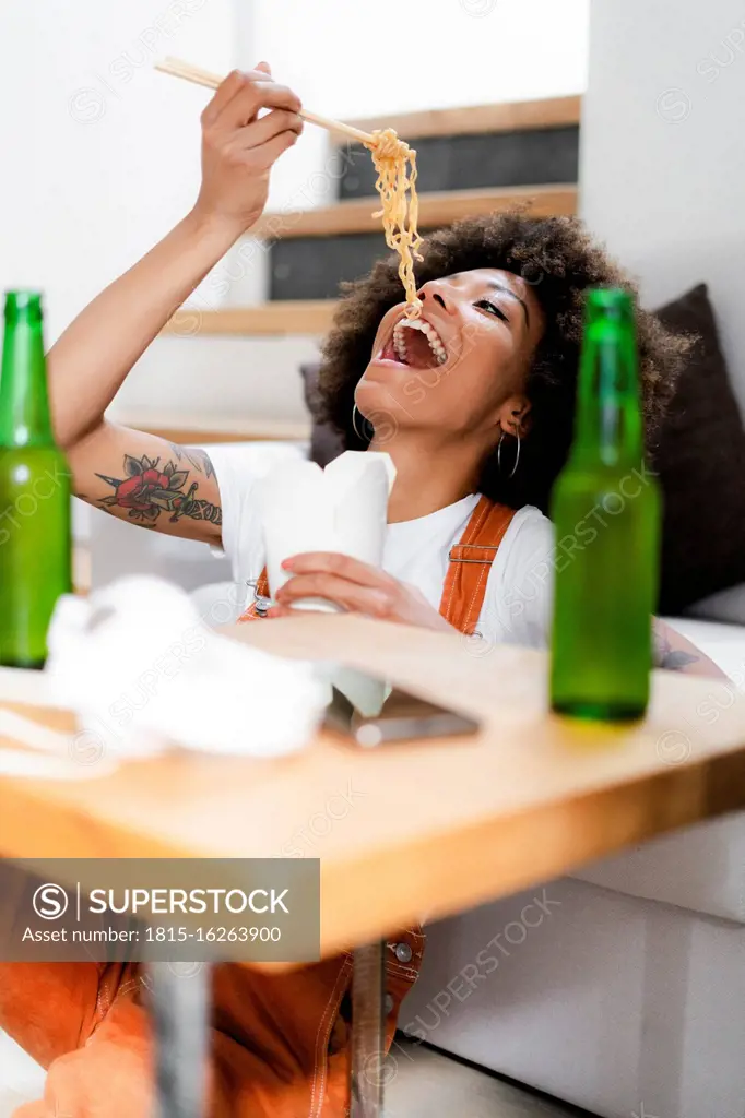 Portrait of young woman eating Asian food at home