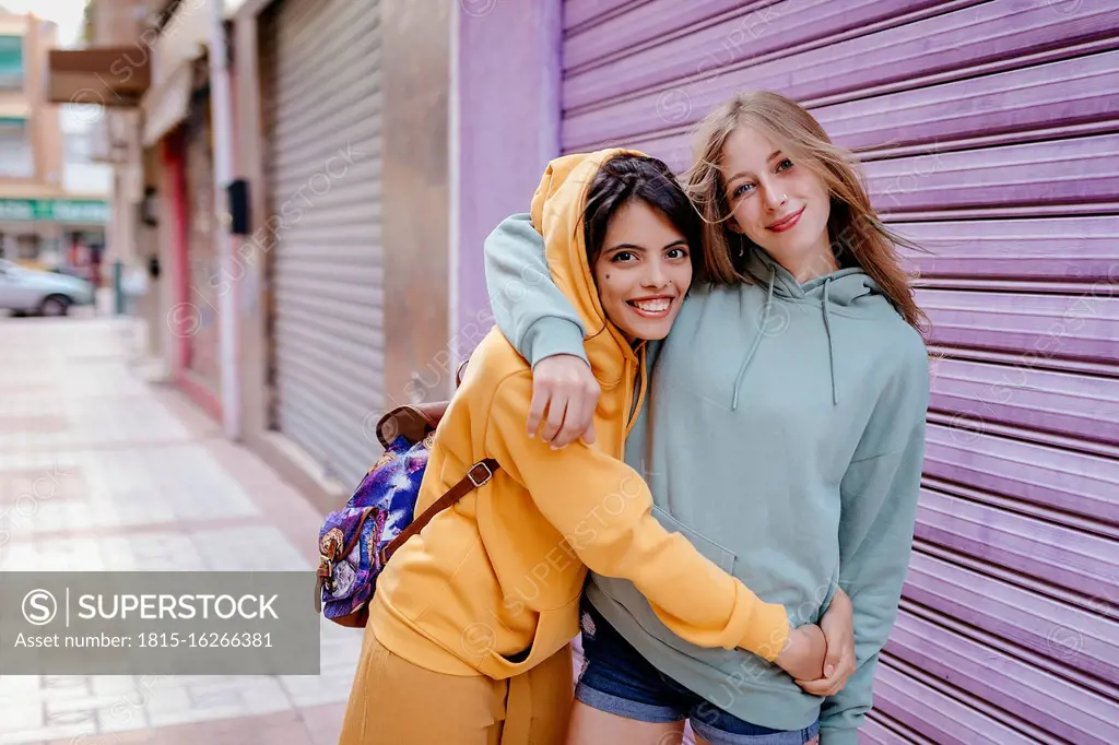 Portrait of two smiling and hugging female friends in the city