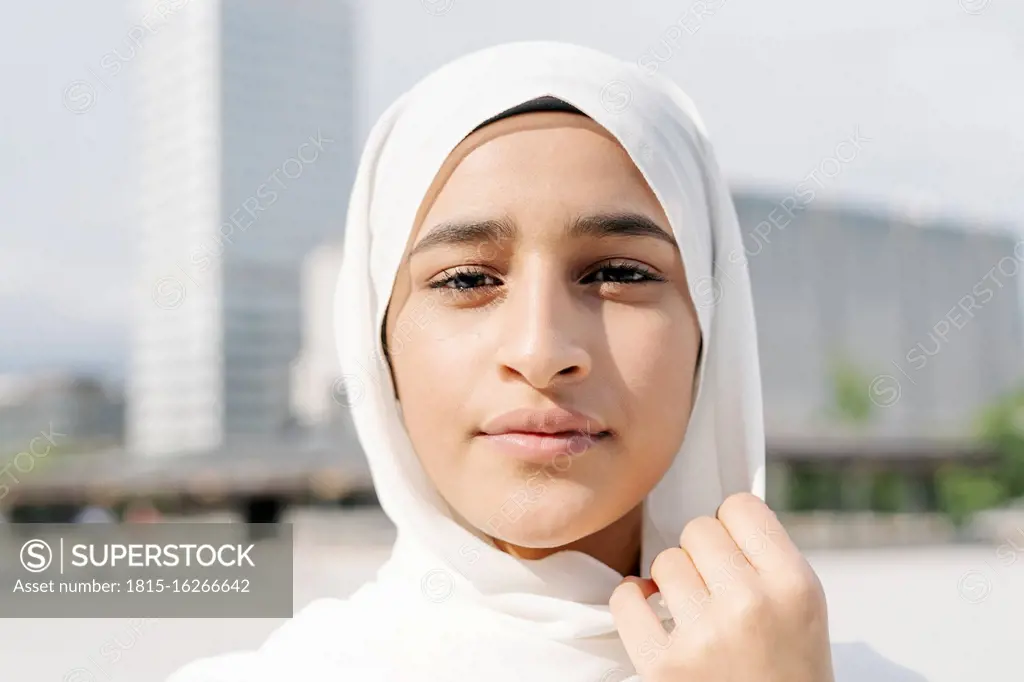 Confident teenage girl wearing headscarf in city during sunny day