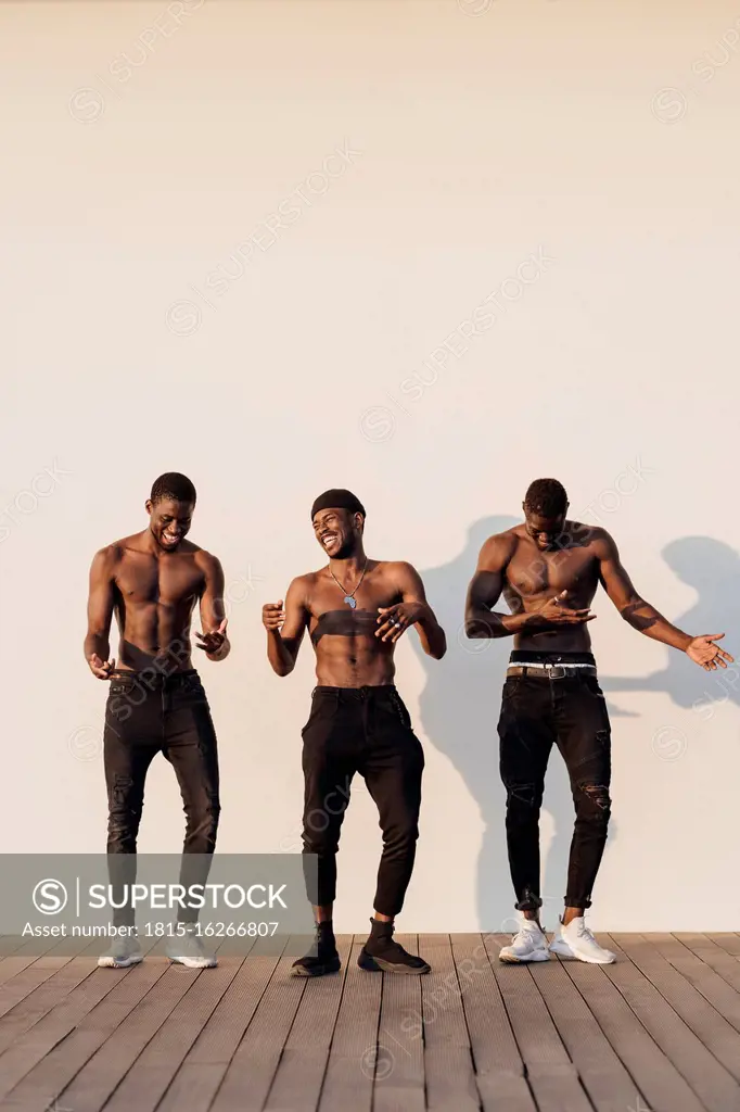 Cheerful young shirtless men standing side by side against white background