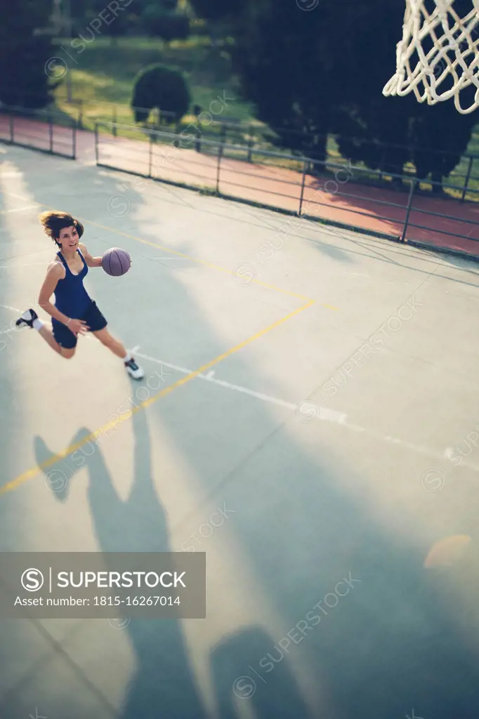 Female athlete running with basketball while practicing on court