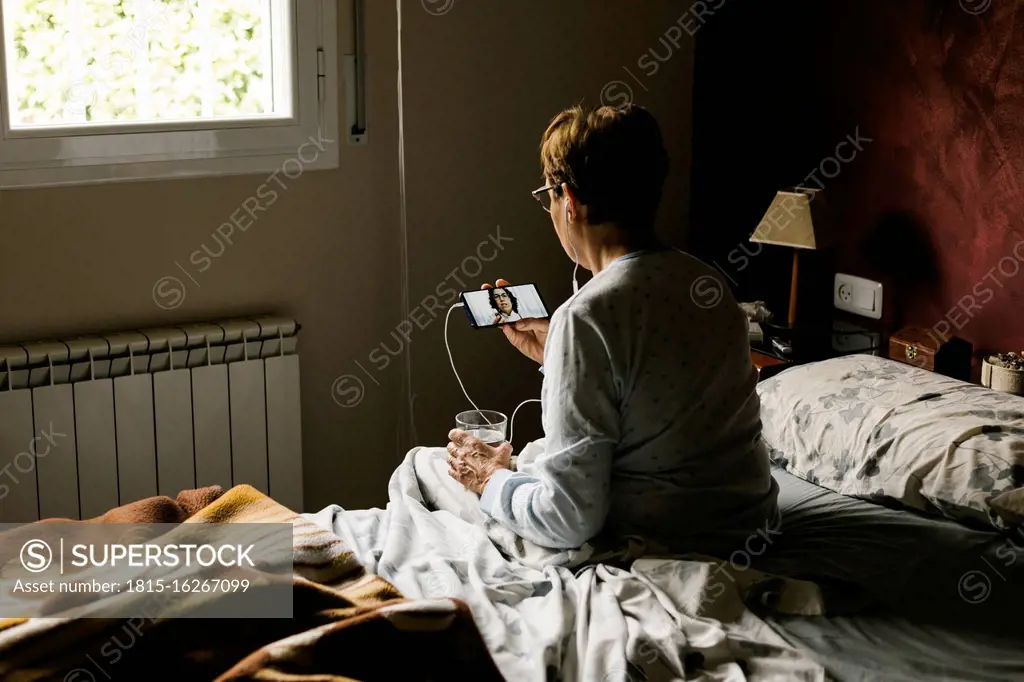 Retired woman on video call with doctor while sitting in bedroom at home