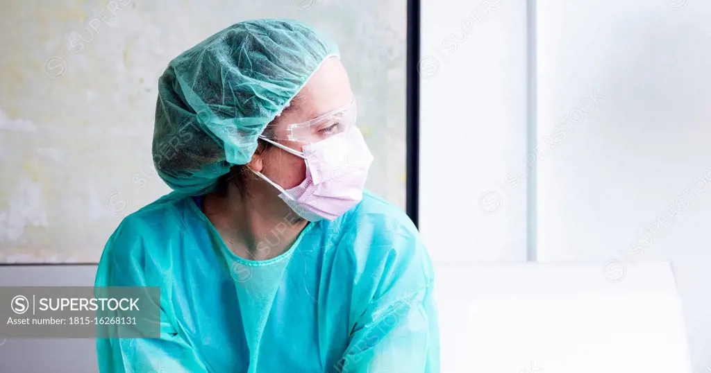 Close-up of thoughtful female doctor sitting against wall in hospital