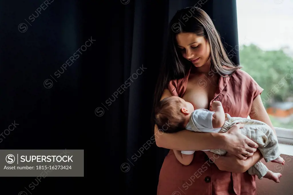 close up of mother breast feeding her newborn baby boy at home