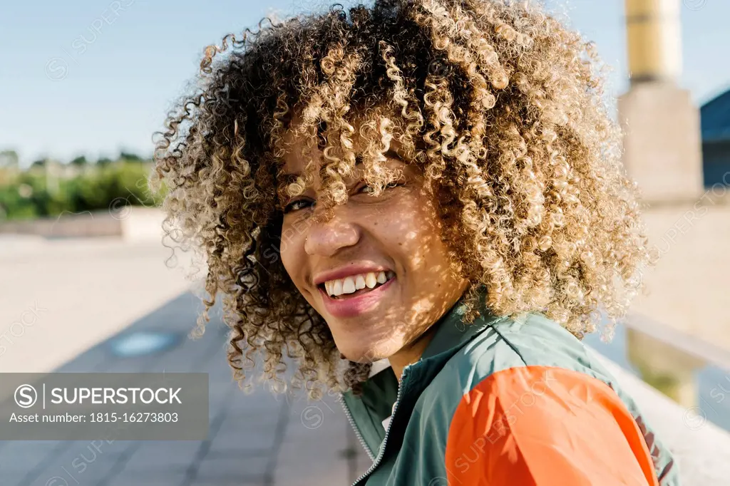 Happy young woman with curly hair during sunny day