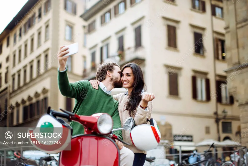 Romantic man taking selfie while kissing woman in Florence city, Italy