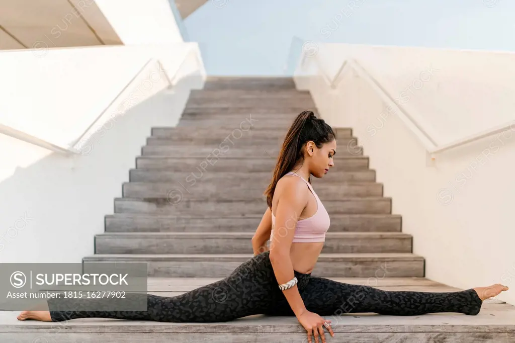 Female athlete with legs apart sitting on wooden steps