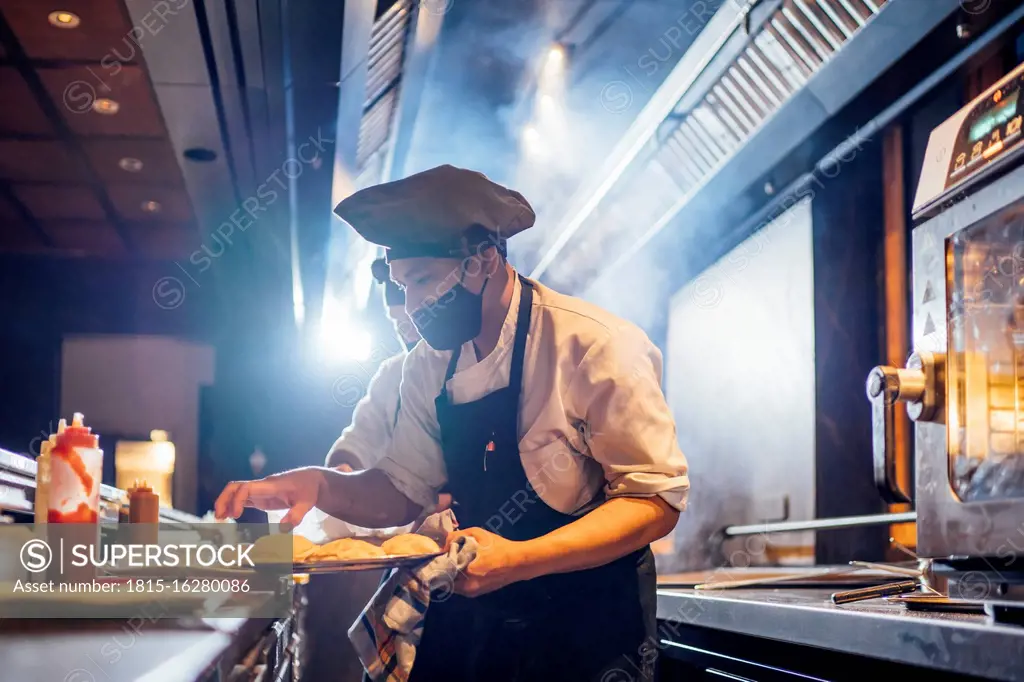 Chef wearing protective face mask preparing a dish in restaurant kitchen