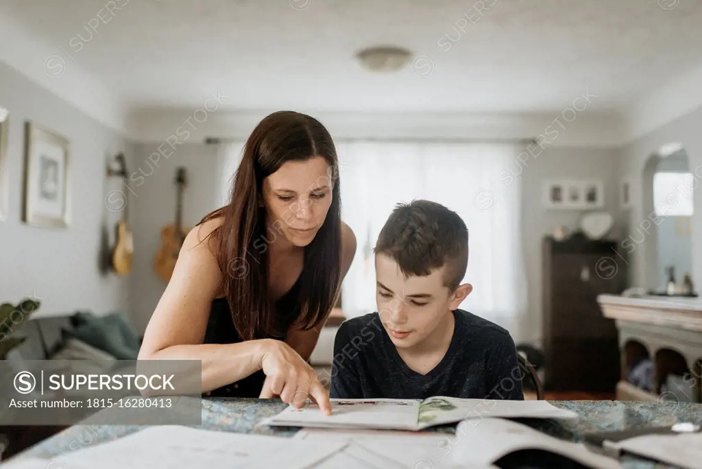 Mother teaching son on table at home during curfew