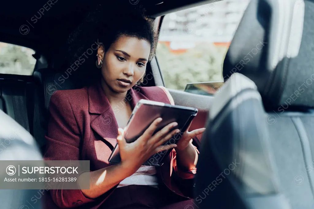 Young female entrepreneur using digital tablet while sitting in car