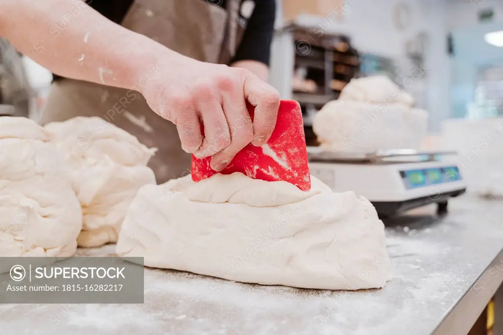 Female baker preparing bread loaf at kitchen counter in bakery