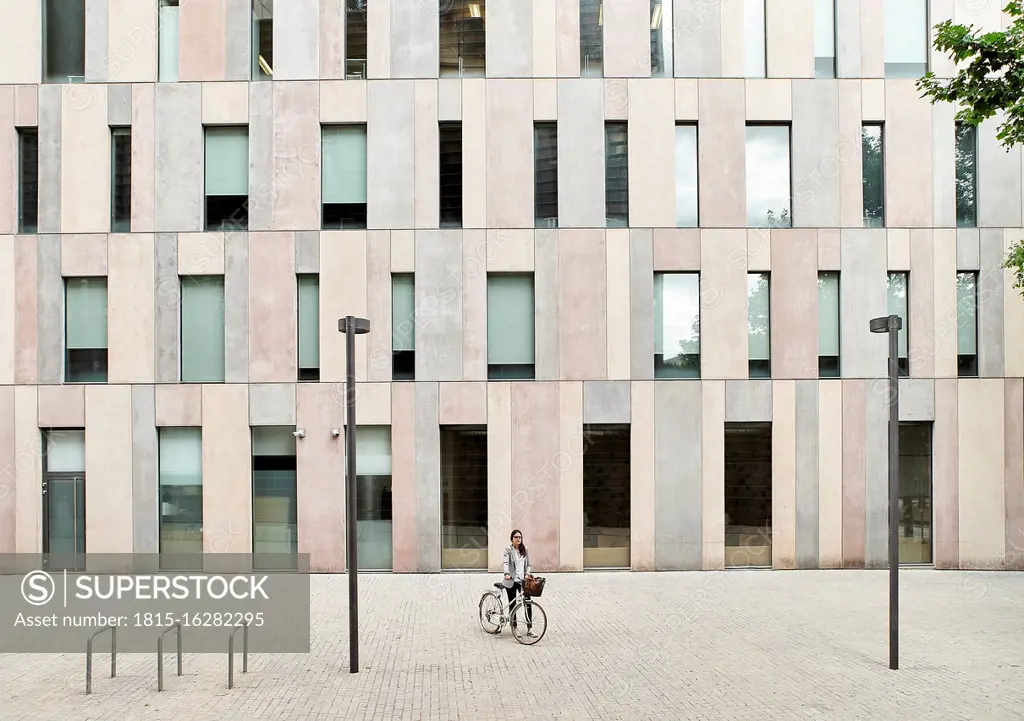 Businesswoman standing with bicycle on street outside office building