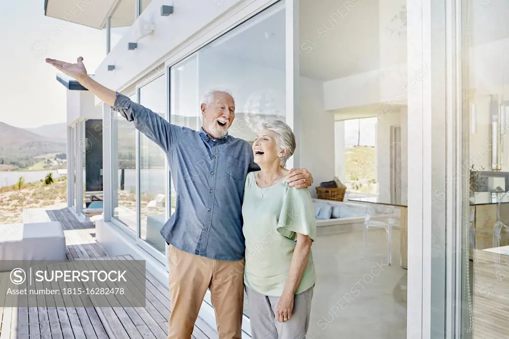 Carefree senior couple standing at luxury beach house