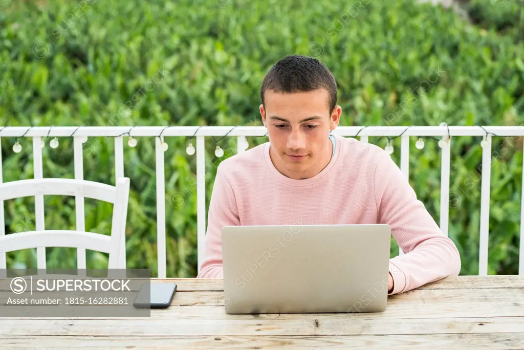 Teenage boy with short hair using laptop at table