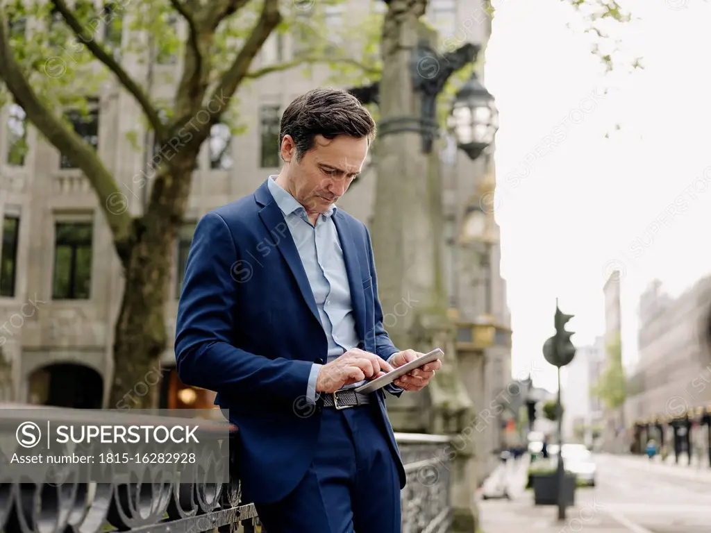 Mature businessman using tablet on a bridge in the city