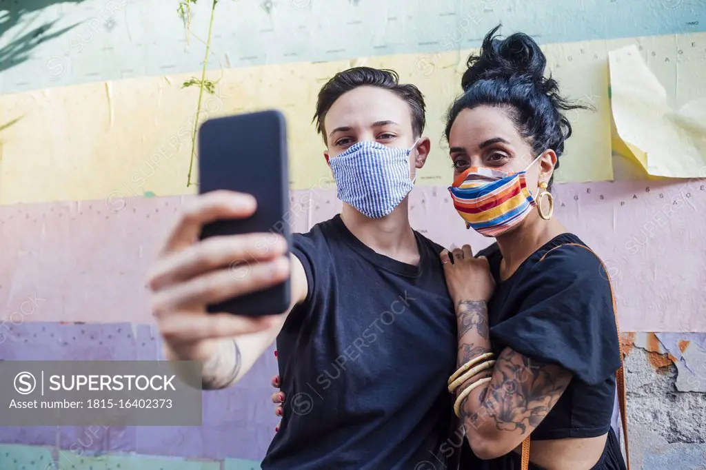 Lesbian couple taking selfie while wearing mask in city