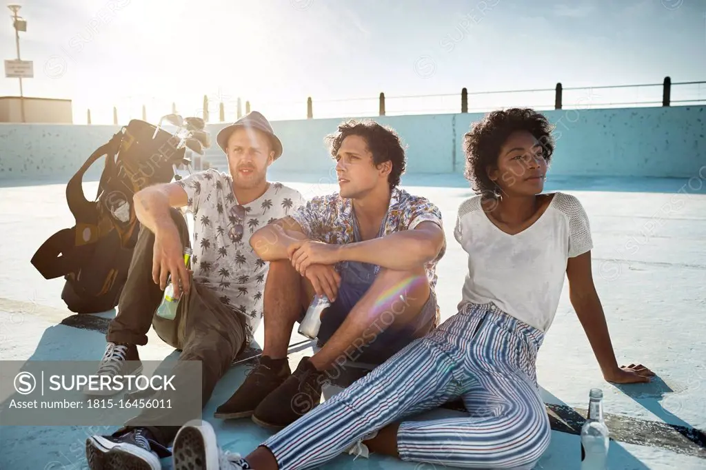 Friends sitting in empty swimming pool with golf clubs