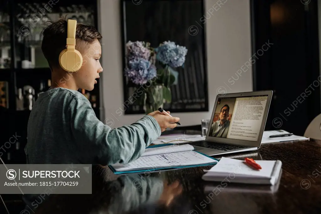 Schoolboy learning at home, using laptop and headphones