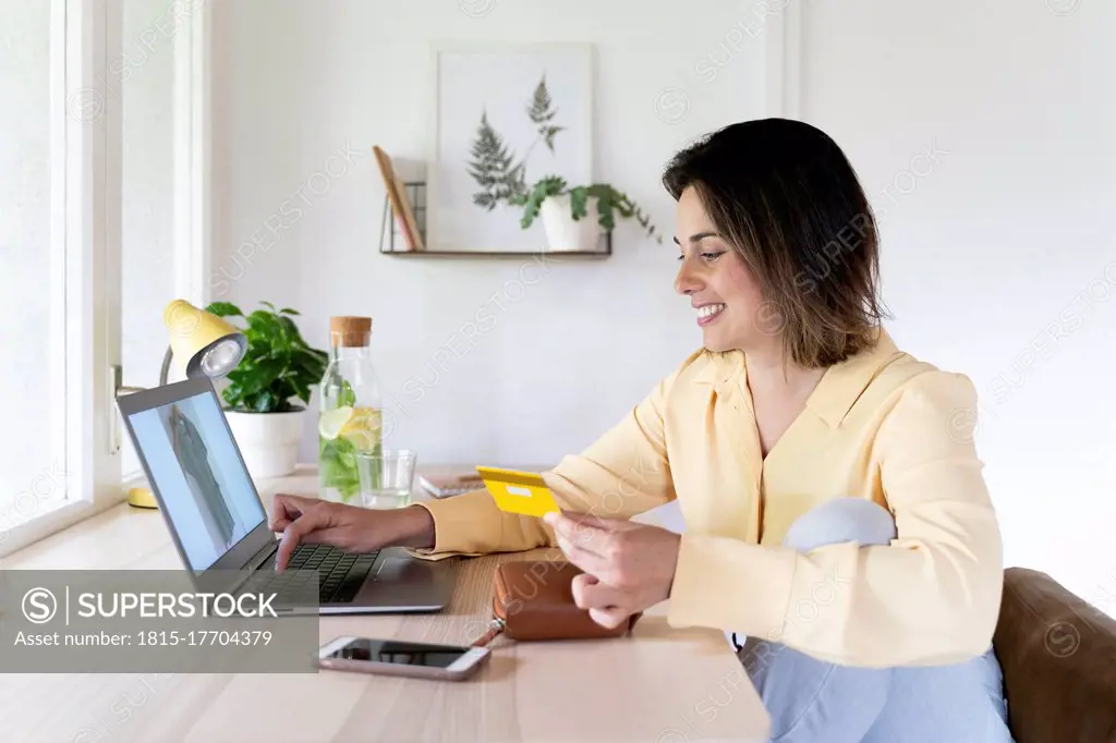 Happy beautiful young woman using laptop for online shopping at home