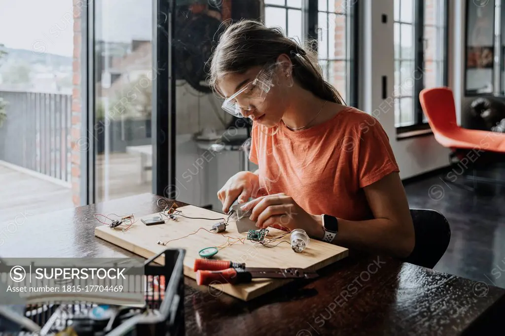 teenage girl tinkering with soldering iron at home