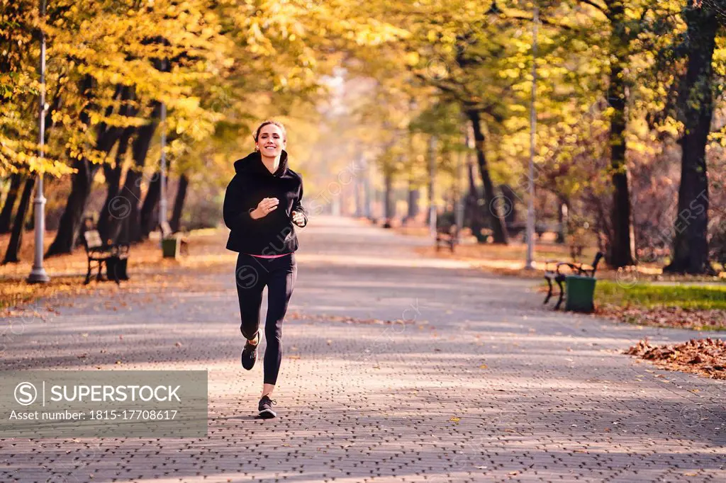 Young woman jogging in autumn forest