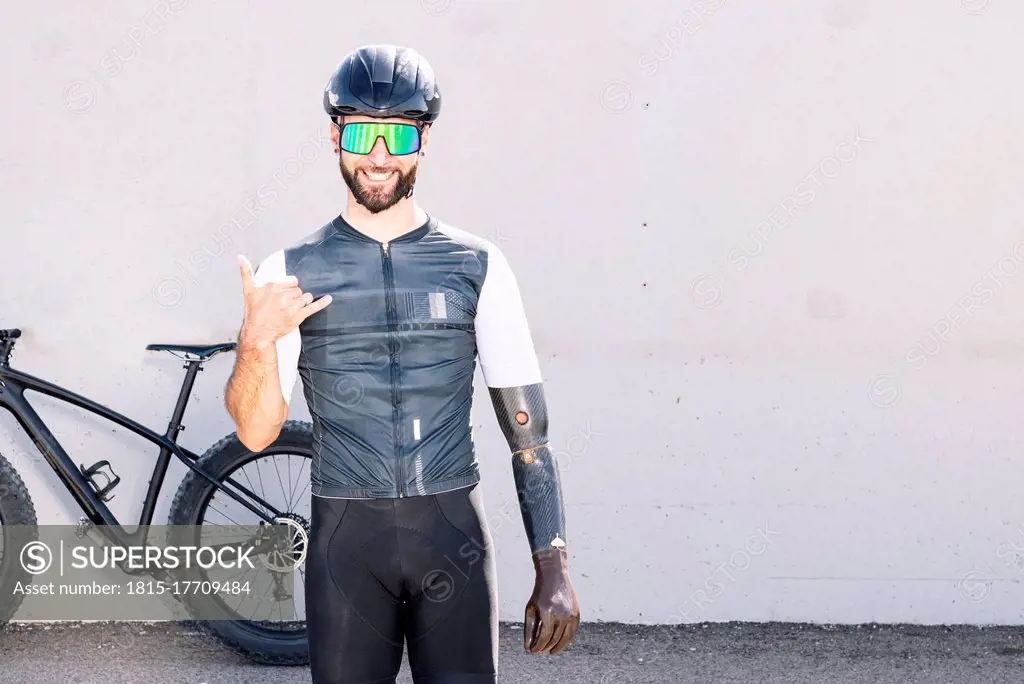 Smiling male adaptive athlete gesturing while standing against wall