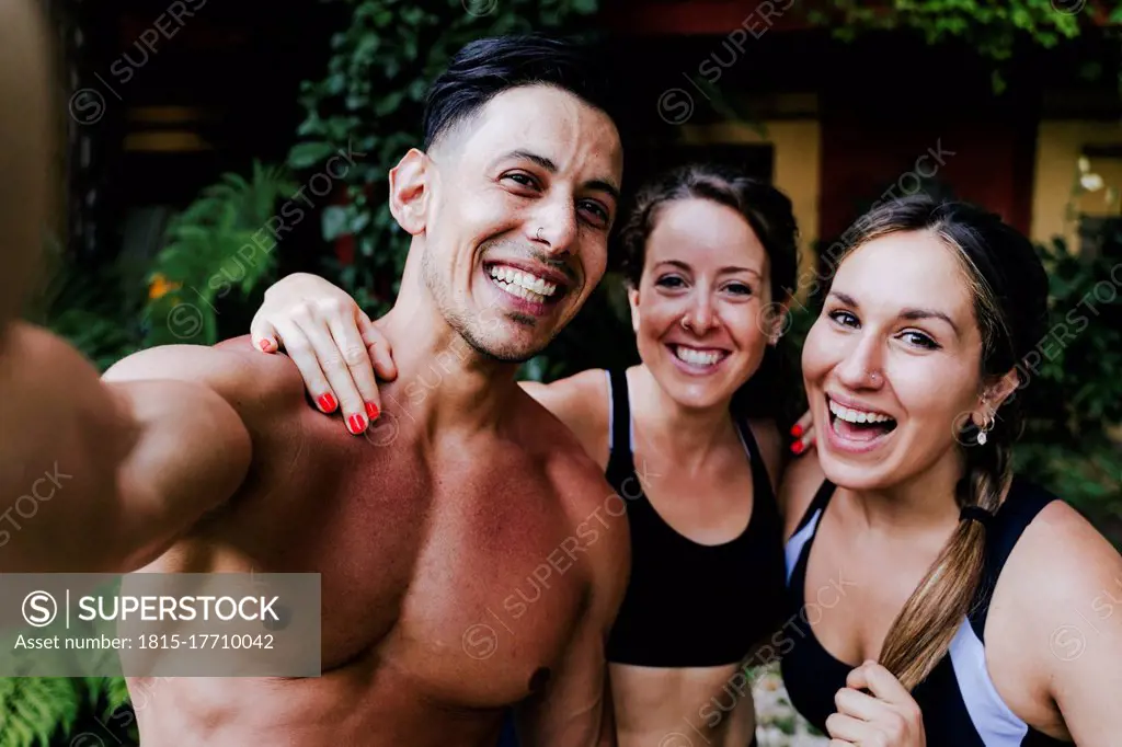 Close-up of shirtless man with cheerful female friends standing in yard