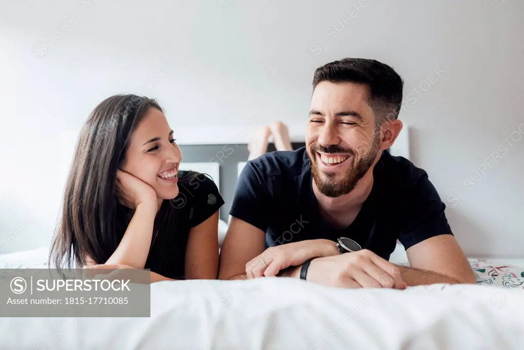 Romantic smiling couple lying on front in bedroom at home