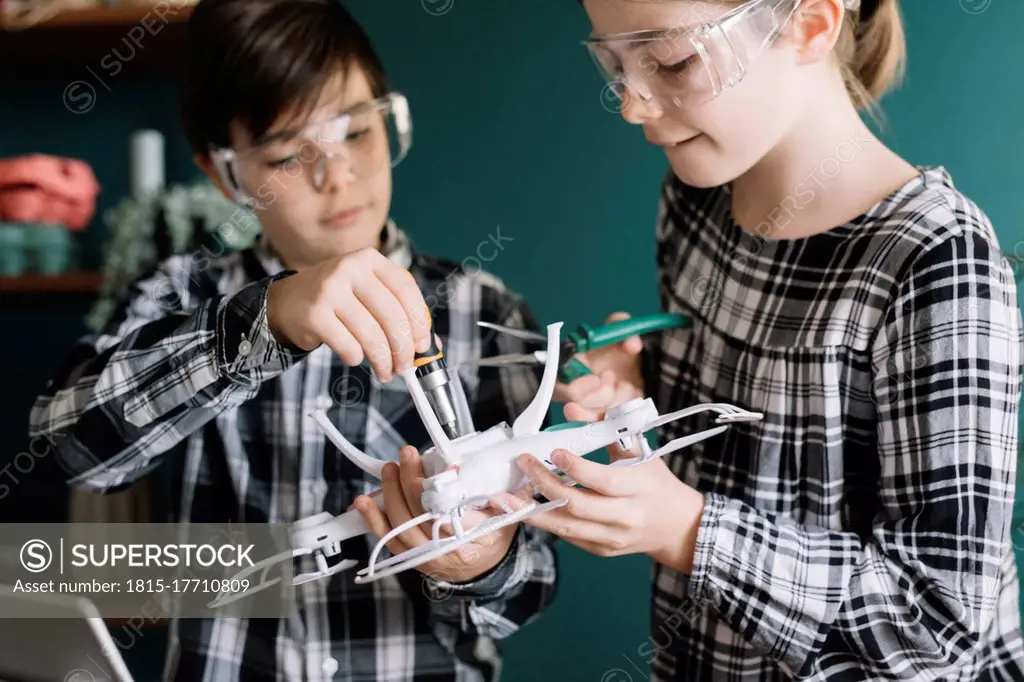 Close-up of siblings making drone at home