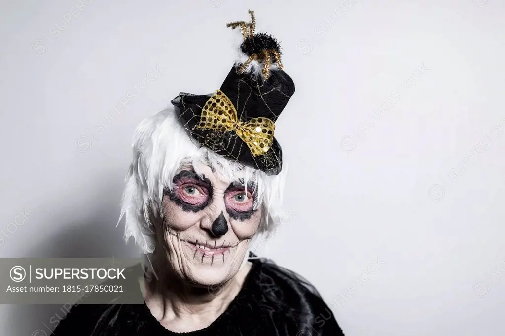 Portrait of senior woman with sugar skull make-up and fancy hat