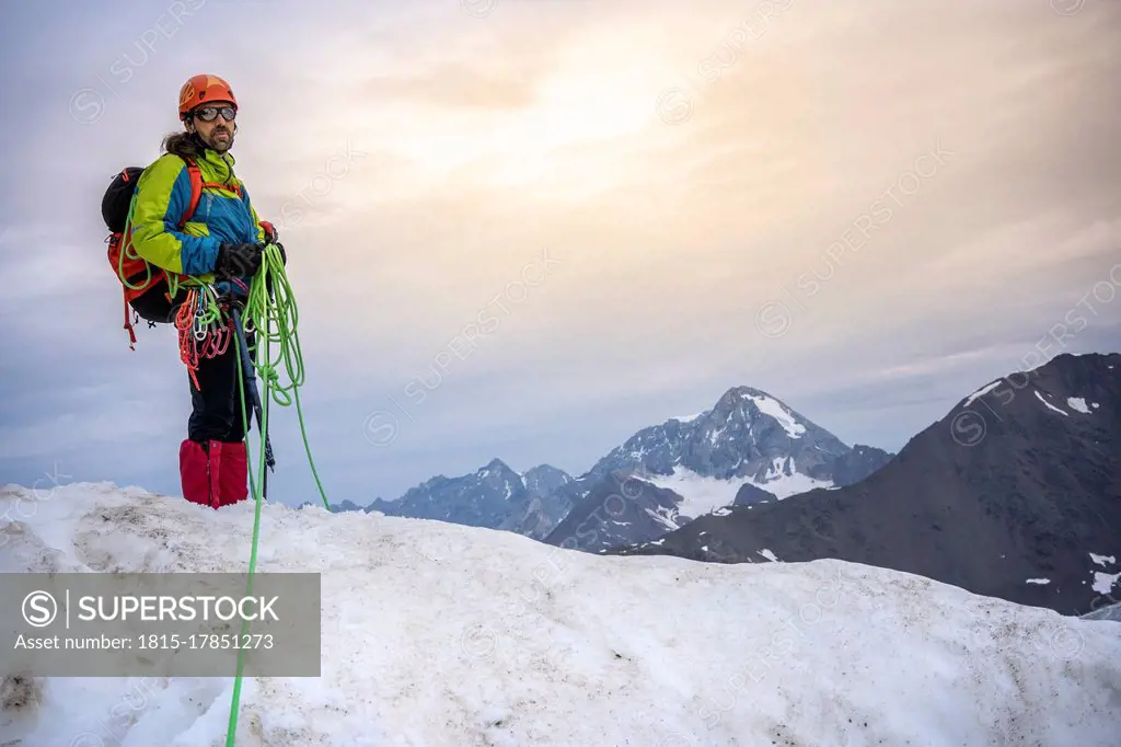 Mature man holding ropes while standing on snowcapped mountain against sky, Stelvio National Park, Italy