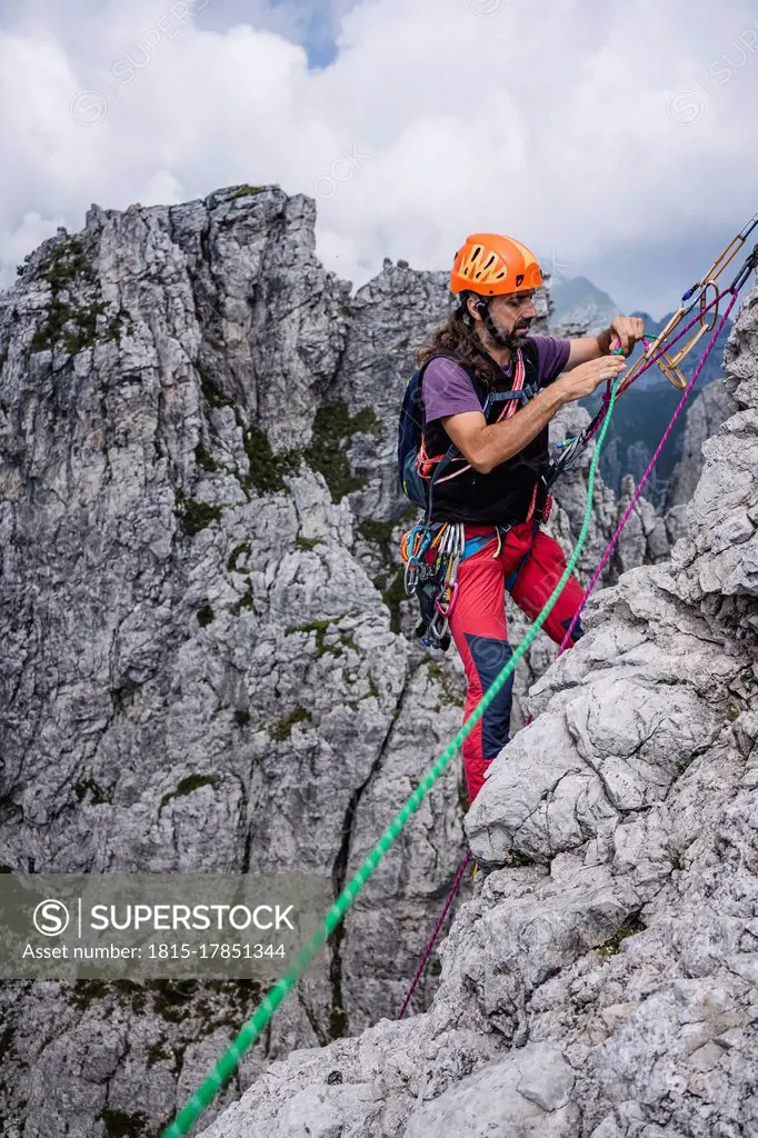 Mature man with ropes standing on mountain, European Alps