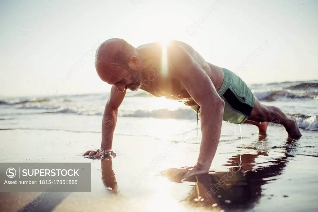 Senior man exercising at beach during sunset