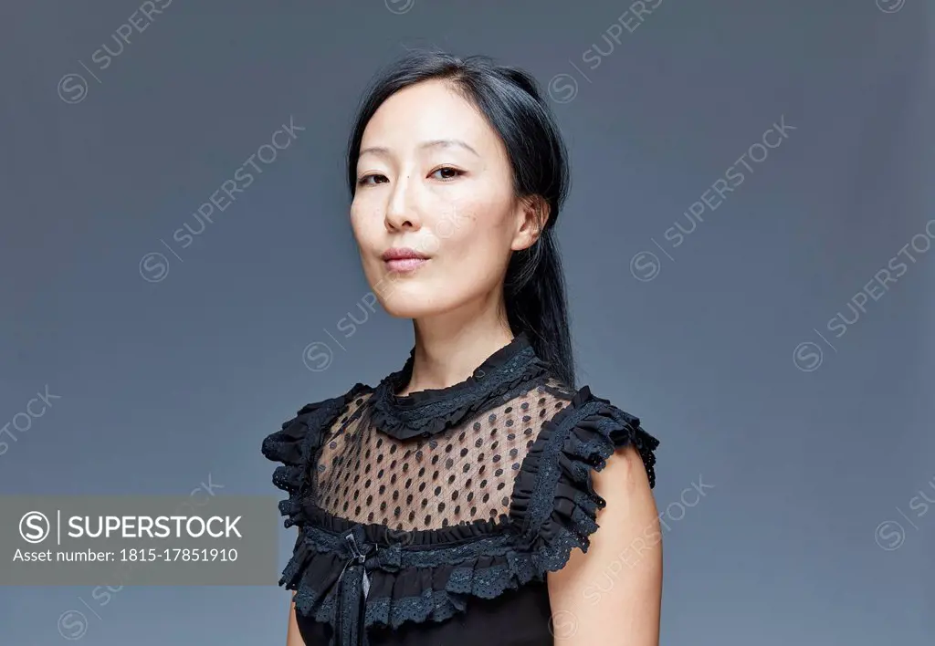 Portrait of self-confident woman in front of grey background