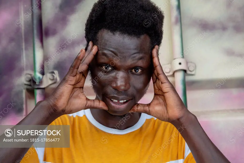 Man with head in hands standing against container