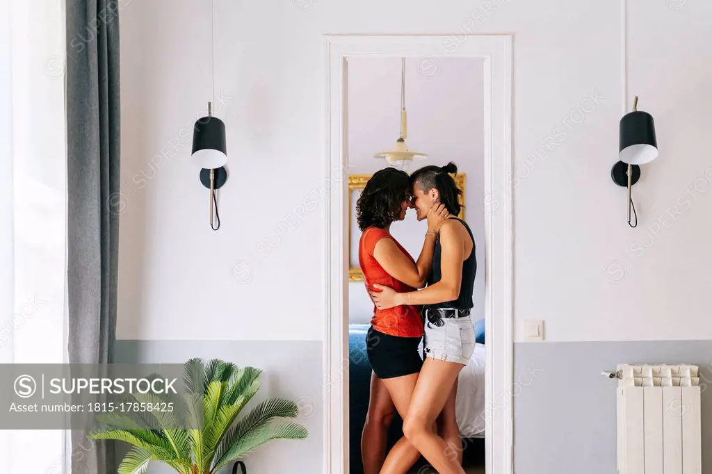 Female friends rubbing nose to each other while standing at doorway