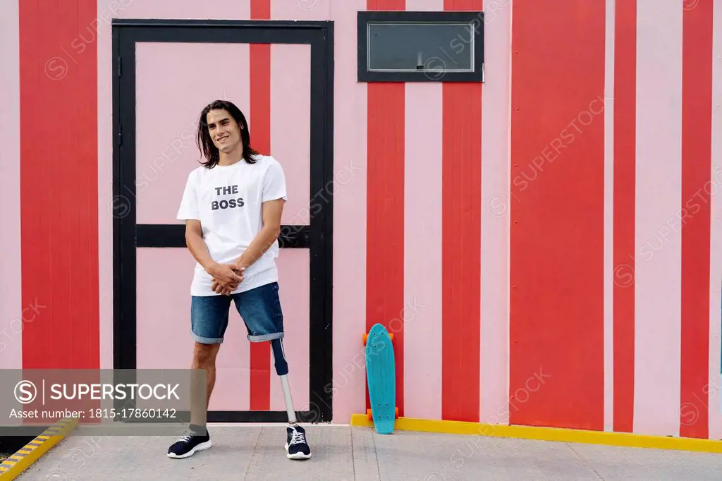 Man smiling while standing against multi colored wall