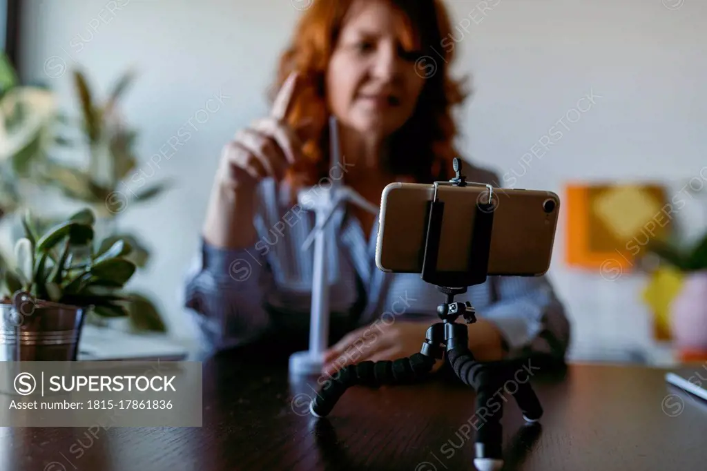 Woman making vlog on mobile phone while sitting at home