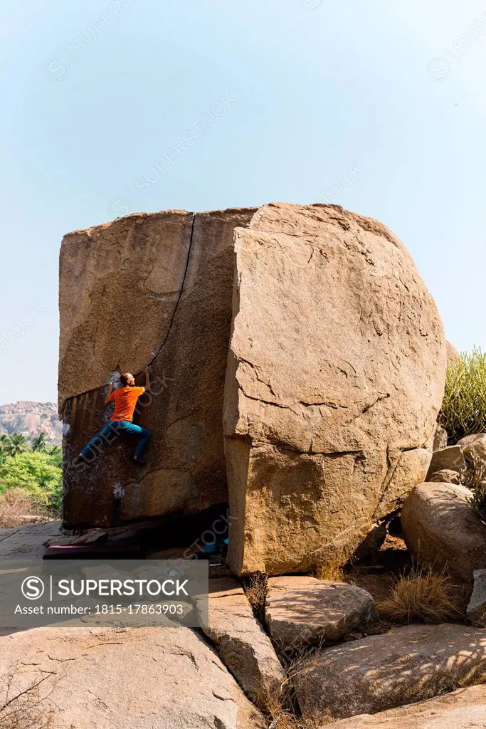 Male rock climber ascending huge boulder